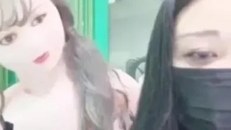 Live-Übertragung einer sexy, großbrüstigen Moderatorin auf dem Handy, die sexy Kleidung trägt und mit einer aufblasbaren Puppe spielt