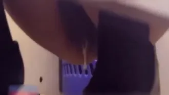 Un type bizarre utilise son appareil portable dans des toilettes publiques pour enregistrer un employé montrant son visage et faisant pipi sur une jeune femme en bas noirs et sa belle chatte.