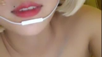 Jolie fille à lunettes se masturbe, nue, se touche avec un bâton de massage et gémit