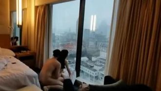 Ein reicher junger Mann der zweiten Generation nahm seine Freundin mit in ein Luxushotel, um Sex zu haben, während er vor den raumhohen Fenstern die Stadtlandschaft überblickte.