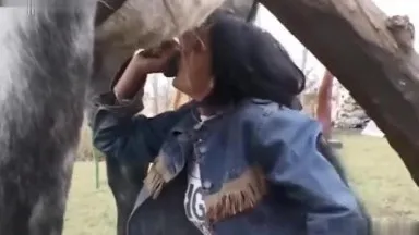 Une femme aux gros seins fait une pipe bâclée à une bite de cheval avant