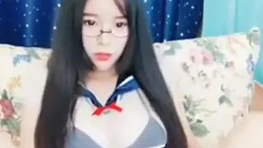 Une jolie fille avec des seins D et des lunettes porte un costume sexy et diffuse des accessoires dans son vagin lors d'une émission en direct