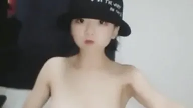 La piccola bellezza che indossa un cappello rotondo nero balla nuda e allarga le gambe per vedere la sua vagina. È molto allettante.