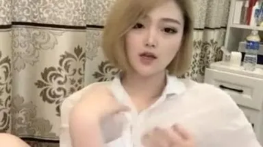 Una linda chica con cabello rubio corto y buena apariencia viste una camisa blanca transmitida en vivo en casa, hurgando constantemente su coño para seducir a los fanáticos.